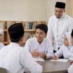 Siswa dalam kelompok kecil berdiskusi dengan pembagian peran sementara guru memantau proses belajar